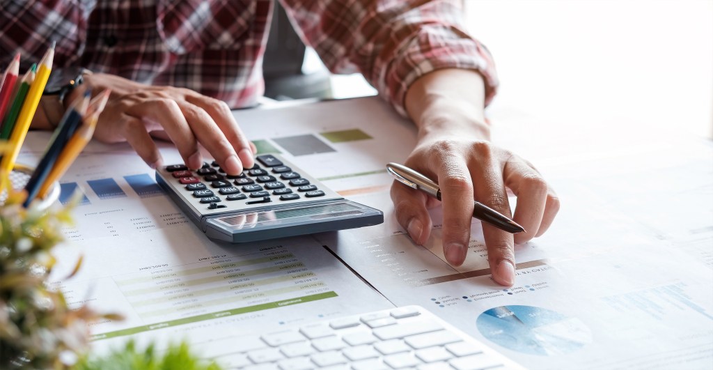 Man analyzing budget with pen and calculator.