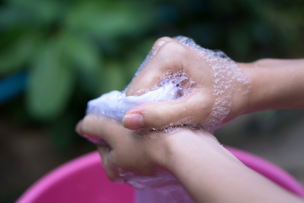 Hand washing clothes in a bucket